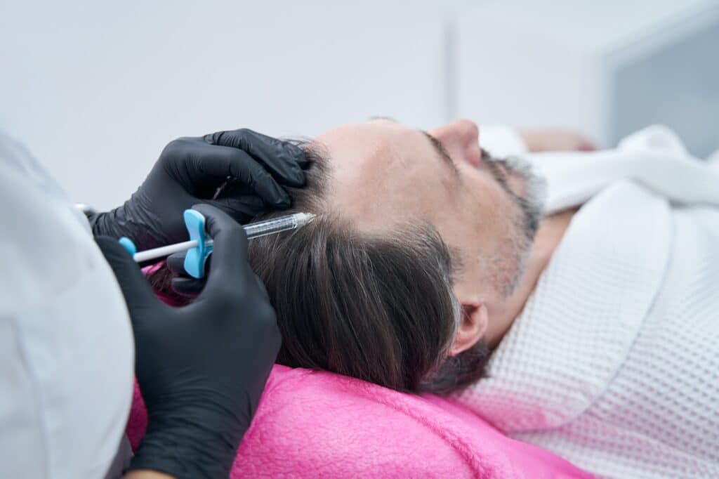 Competent medical worker doing procedure for hair growth