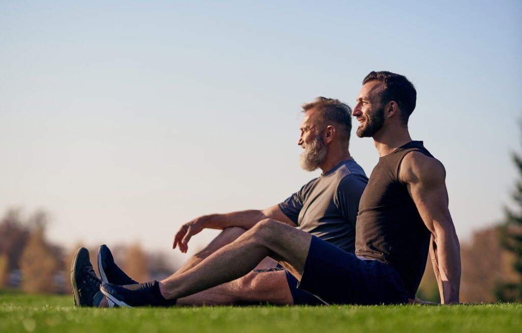 The old and young sportsmen sitting on the grass.